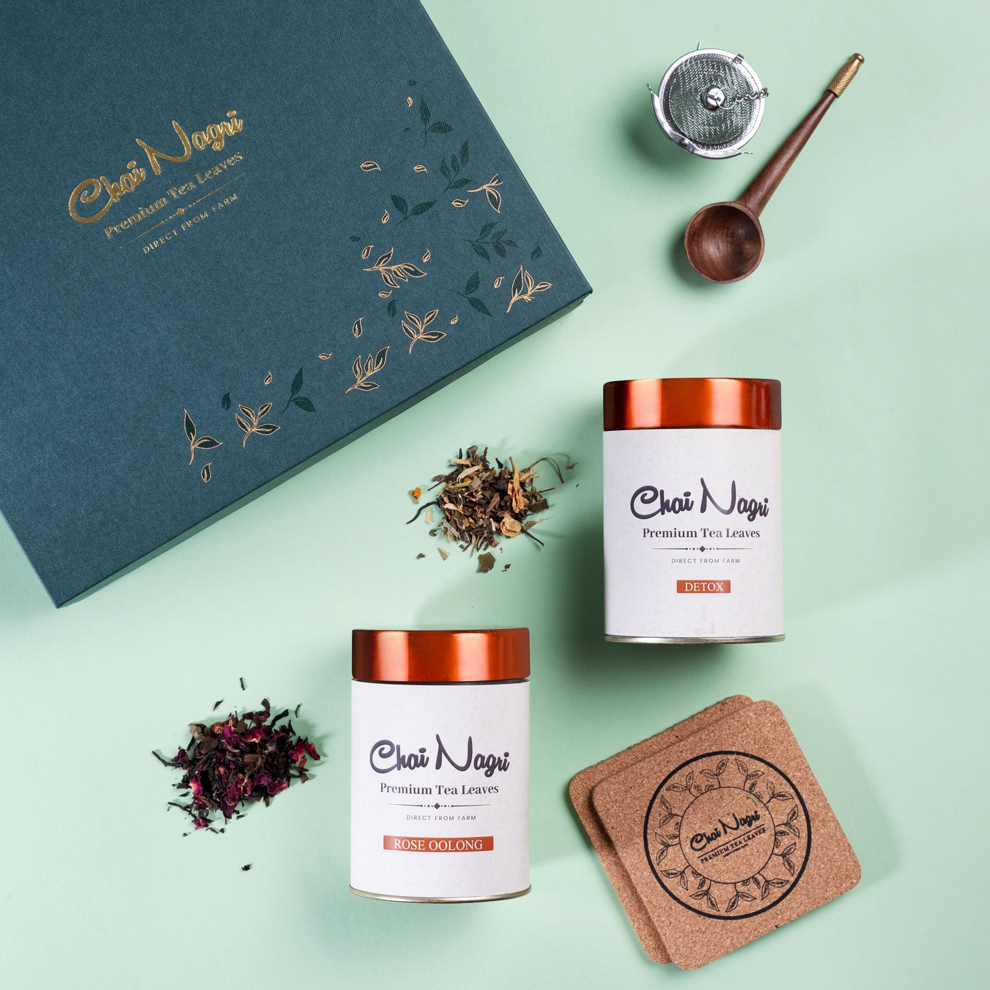 Geöffnete grüne Royal Teebox mit Detox- und Rose-Oolong-Tee, Holzlöffel, Sieb und Untersetzern.