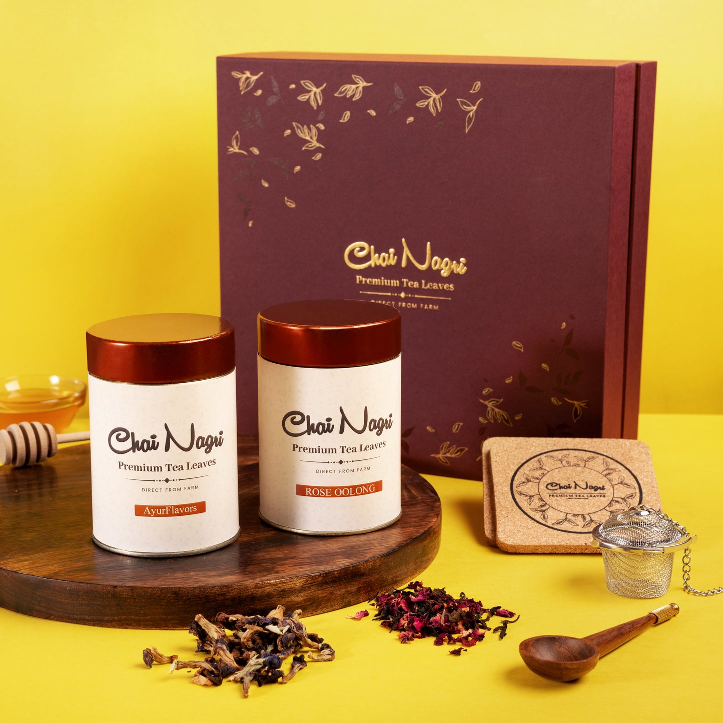 Chai Nagri Teebox mit AyurFlavors und Rose Oolong, dekorativ auf Holzbrett mit Blüten präsentiert.